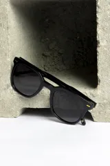 Lentes de sol negros con montura cuadrada y detalles dorados en las esquinas.