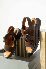 Sandalias de cuero color marrón y blanco, con suela track negra y ajuste con velcro.