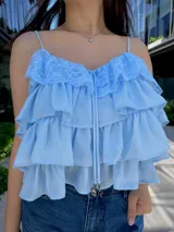 Blusa color amarillo manteca con breteles finos, escote en V con detalle de encaje y volados en capas.