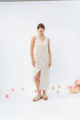 Vestido midi de lino en color natural, con escote en V y abotonado frontal con botones de madera. Presenta un diseño de corte recto y fluido, sin mangas.