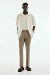Pantalón de vestir color beige, corte slim fit, con cierre de botón, bolsillos laterales y bolsillos traseros ribeteados con botón.