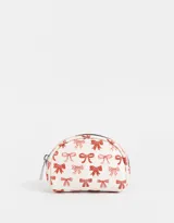 Monedero pequeño de cuerina color blanco con estampado de moños rojos y rosados, y cierre de cremallera.