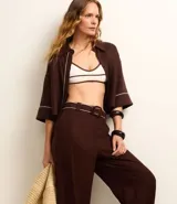 Pantalón wide leg de cintura alta color marrón, confeccionado en viscolino con 15% de lino, con trabillas en la cintura y vieses contrastantes en las barras. Incluye cinturón de tejido con hebilla metalizada de efecto martillado.