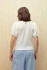 Top negro de tejido texturizado con mangas cortas abullonadas y cuello redondo.