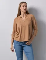 Blusa color camel de poliéster y elastano, con cuello a la base, escote en V y mangas tres cuartos. Presenta dos bolsillos frontales con cierre metálico.
