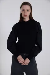 Sweater negro de punto con cuello alto y mangas largas abullonadas de poplín.
