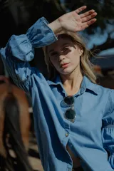 Camisa celeste de jean fino, con cuello clásico, cierre frontal con botones y mangas largas abullonadas con puños elastizados.