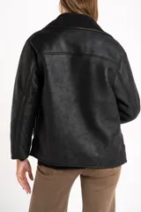 Chaqueta tipo gamulán de color negro con forro de corderito sintético al tono. Presenta solapas anchas, cierre frontal con botones y un diseño entallado al cuerpo.