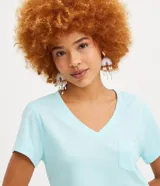 Blusa blanca de algodón con cuello en V, manga corta y bolsillo frontal.