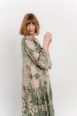 Vestido largo azul con estampado floral en tonos beige, confeccionado en viscosa. Presenta escote en V, botonadura completa en el frente y mangas largas con volados.