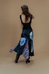 Falda larga negra con estampado de flores y diseño irregular con tajos y paneles de tela estampada a cuadros en tonos rojo, azul y blanco.
