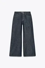 Pantalón de jean azul oscuro, de tiro alto y corte wide leg. Tiene cinco bolsillos, cierre frontal con cremallera y botón.