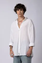 Camisa blanca de lino con cuello clásico, manga larga con puños abotonados y corte holgado. 