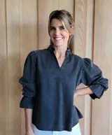 Blusa azul con diseño de cuello alto y mangas abullonadas, confeccionada en material de mezclilla.