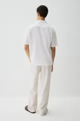 Camisa blanca de manga corta en mezcla de algodón y lino. Modelo con cuello abierto, tapeta lisa y bolsillo superior abierto.