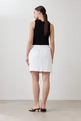 Minifalda blanca de corte recto, con pretina elastizada con cordón ajustable y bolsillos laterales.