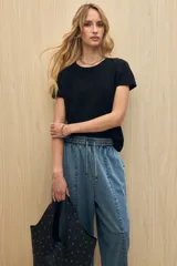 Remera negra de manga corta confeccionada en algodón con textura liviana y suave al tacto. Presenta costuras decorativas en los laterales y mangas con pequeño doblez que aportan un toque relajado.