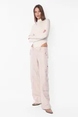 Body manga larga color beige, de punto roma, con cuello medio alto con cierre de nylon a tono. Tiene recortes pisados con bordador, mangas ranglan con mitones en los puños, broches snap en la entrepierna y elástico interno en el contorno de tiro.