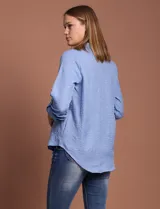 Blusa celeste con escote en V y mangas 3/4 regulables con presilla y botón.