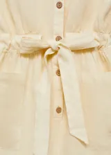 Mono corto color crema de lino con cuello camisero, manga corta, dos bolsillos de parche delanteros, cintura elástica con lazo y cierre frontal con botones.