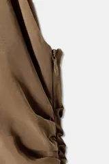 Vestido corto marrón con cuello halter que se ata al cuello, detalle de frunces en la falda y volados asimétricos en el ruedo.