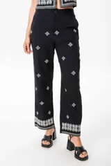 Conjunto de chaleco y pantalón de lino negro con bordado blanco. El chaleco es abierto con tiras ajustables y el pantalón es de corte sastrero con elástico en la parte trasera de la cintura.