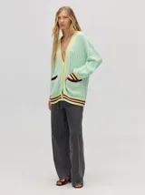 Cardigan largo color crema con detalles en color camel en el borde de los bolsillos, en el borde de los botones y en los puños. Tiene cuello en V y cierre con botones.