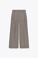 Pantalón de tiro alto con estampado de cuadros en tonos marrón y beige, con bolsillos delanteros y falsos bolsillos traseros. Detalle de trabillas con botones en la cintura. Cierre frontal con cremallera y ganchos metálicos.