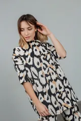 Remerón de tela tejida con estampado animal print en tonos rosa y negro, cuello alto y mangas cortas.
