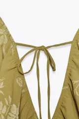 Top amarillo con estampado floral en jacquard, escote en pico, mangas cortas abullonadas con elástico, cintura elástica y espalda descubierta ajustable con lazos.