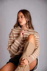 Sweater de punto color beige con rayas horizontales blancas, cuello polo con cierre de cremallera y mangas largas.
