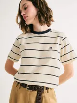 Remera de manga corta color crudo con rayas horizontales negras, cuello redondo con ribete negro y logo bordado en el pecho. Corte clásico.