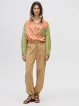 Mono largo de jean celeste con corte holgado, cintura elastizada con cordón ajustable, sin mangas, cuello camisero y cierre frontal con botones. Presenta bordados de motivos playeros en el pecho.