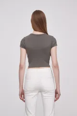 Remera gris de corte crop con cuello redondo y mangas cortas. Estampado frontal con alas y texto "Angel on Earth".