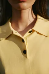 Top azul eléctrico de punto, con cuello polo, manga corta y cierre frontal con botones negros.