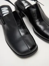 Mocasines color beige con taco bloque de madera color negro y correa trasera ajustable.