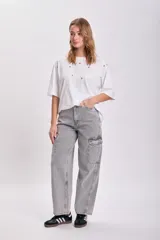 Remera blanca de corte holgado con mangas cortas y detalle de ojalillos metálicos en el frente.