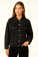 Campera de jean azul con cuello clásico, cierre frontal con botones dorados, bolsillos con solapa abotonada en el pecho y corte holgado.