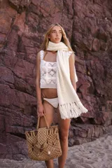 Bufanda tejida color crema, de punto grueso con flecos largos en los extremos.