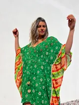 Túnica corta verde con estampado de flores blancas y detalles bordados en el escote. Mangas anchas con terminación en tela estampada a rayas naranjas y blancas.