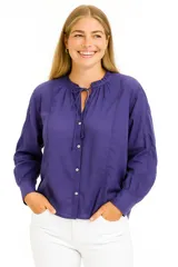 Blusa blanca de manga larga con cuello mao con lazo y cierre frontal con botones.