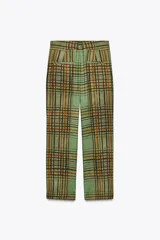 Pantalón de tiro medio con estampado de cuadros color verde y marrón, confeccionado en hilatura de viscosa. Tiene bolsillos delanteros, corte crop y bajo acampanado. Cierre frontal con cremallera y botón.