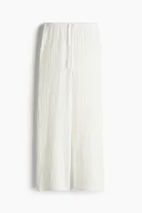 Pantalón recto blanco de punto con textura arrugada, cintura elástica y cordón ajustable.
