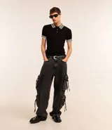 Pantalón de jean super baggy color gris oscuro, con trabillas en la cintura, bolsillos laterales tipo cargo con cordones ajustables y cierre frontal con cremallera y botón.