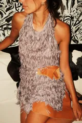 Vestido minifalda blanco con cuello halter, confeccionado en tela de flecos y lentejuelas, con espalda al aire.