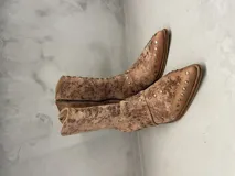 Bota de cuero color marrón con tachas metálicas, taco de 5 cm y cierre lateral.