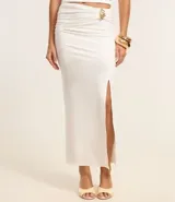 Conjunto de dos piezas color blanco, compuesto por un top tipo corset strapless con escote en V y una pollera midi ajustada con fruncido lateral y abertura alta, asegurada con un adorno metálico.