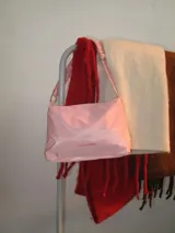 Cartera bandolera rosa de lona semi impermeable con cierre metálico, forrería de gross y bolsillo interno. Tiene tira regulable para usar al hombro, cruzada o como riñonera.