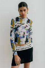 Top de microtul traslúcido con cuello alto y mangas largas. Presenta un estampado abstracto con manchas de colores azul, verde, amarillo y negro.