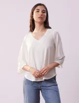 Blusa color blanco con escote en V y aplique de crochet.